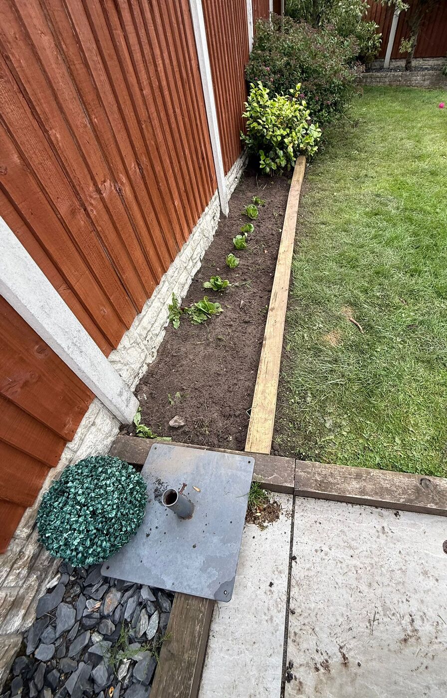 Decorative stone and gravel border with paving slabs against a fence
