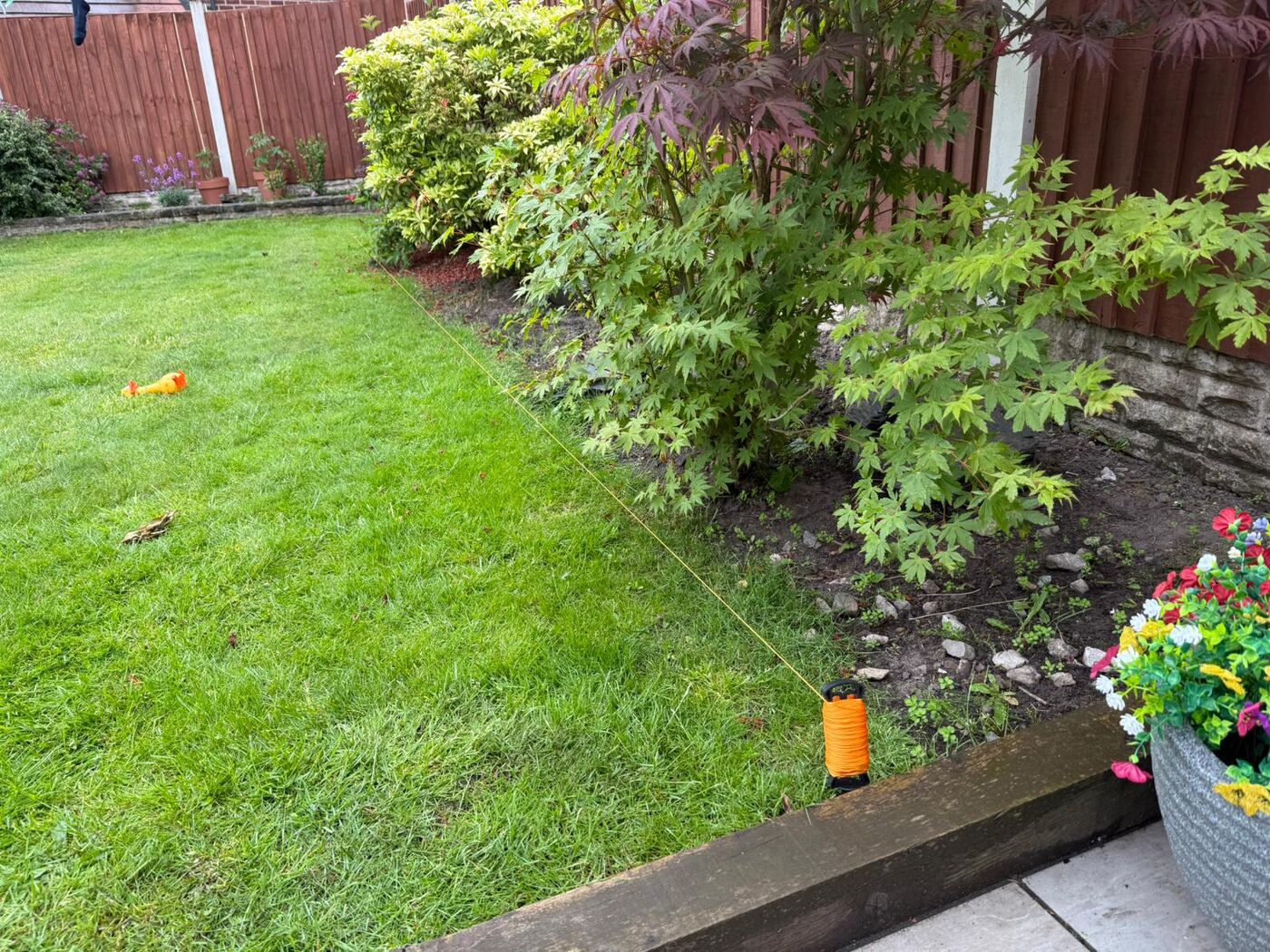 Freshly landscaped back garden with neat lawn, mature shrubs and planted borders