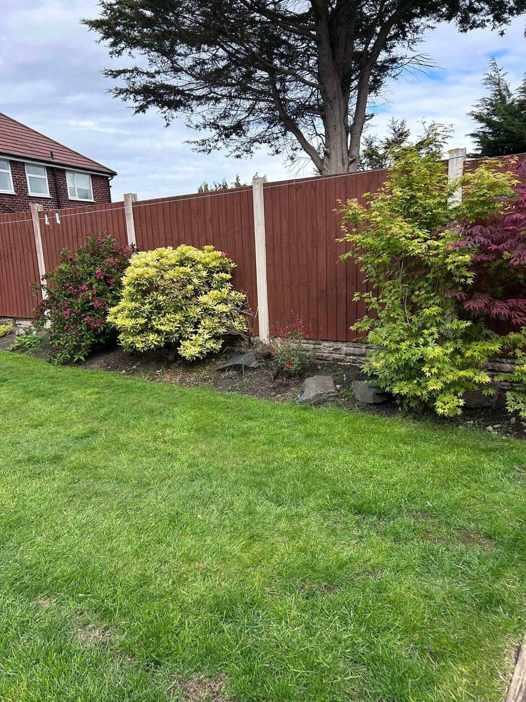Colourful planted border and shrubs alongside a smart lawn and fence